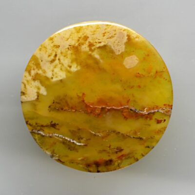 A round piece of yellow agate on a white surface.