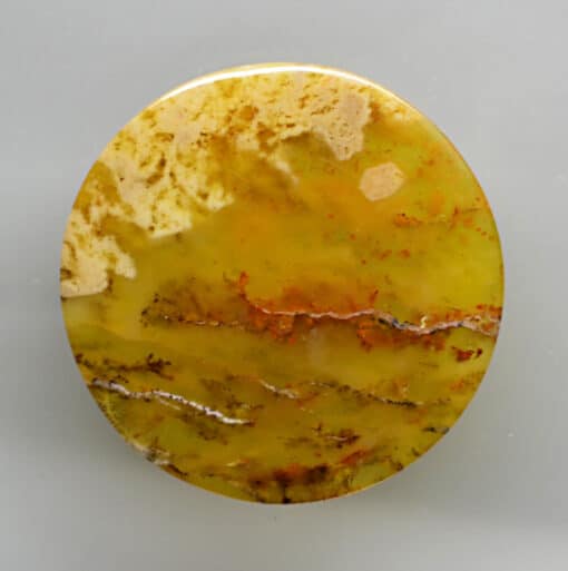 A round piece of yellow agate on a white surface.