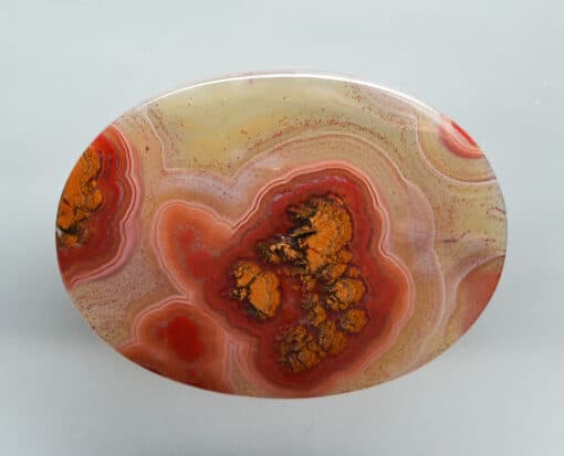 A round piece of agate with orange and brown swirls.