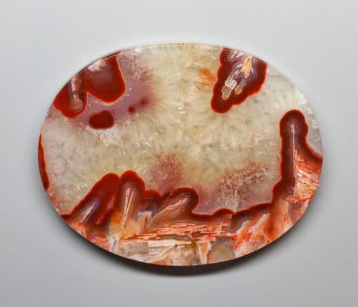 A round piece of agate with red and orange swirls.