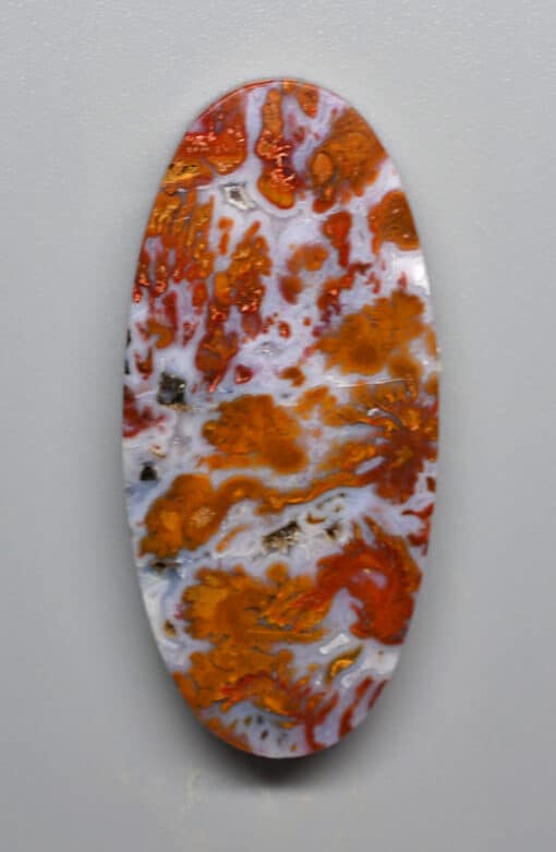 A piece of orange and white marble on a white surface.