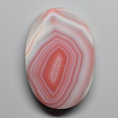 A pink and white agate pendant on a white surface.