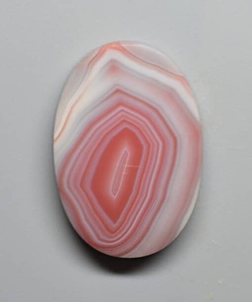 A pink and white agate pendant on a white surface.