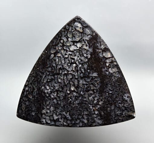 A triangular piece of black rock on a white background.