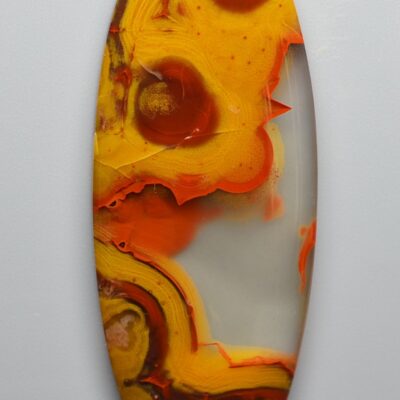 An orange and yellow agate oval on a white surface.