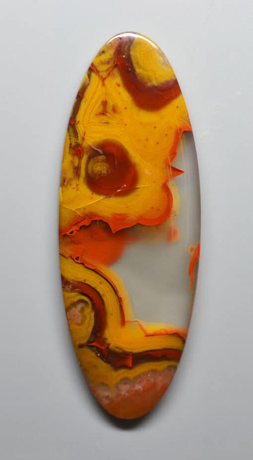 An orange and yellow agate oval on a white surface.