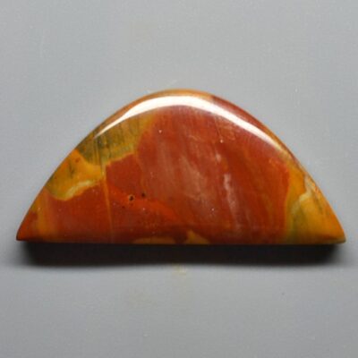 A piece of red and orange jasper on a gray surface.