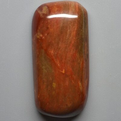 A piece of red jasper on a gray surface.