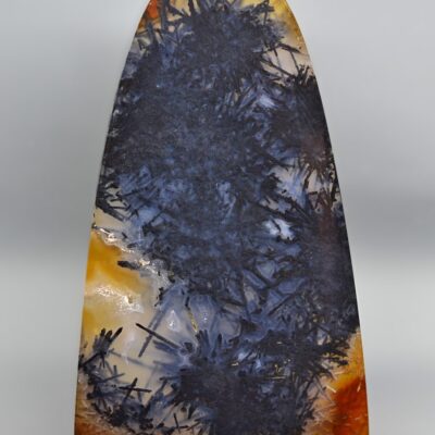 A piece of agate with orange and black paint on it.