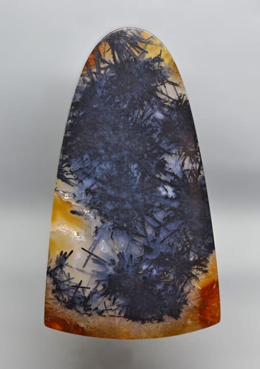 A piece of agate with orange and black paint on it.