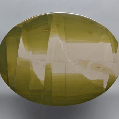 A round piece of green agate on a gray background.