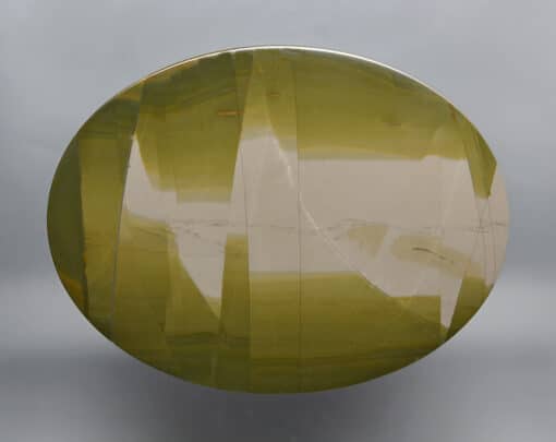 A round piece of green agate on a gray background.