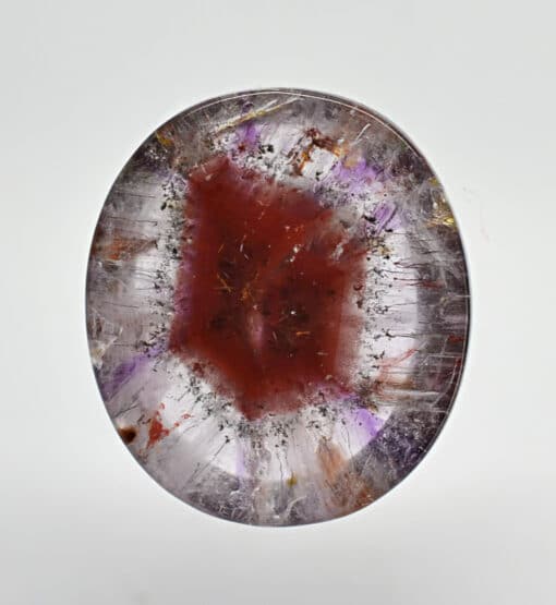 An amethyst crystal with purple and red streaks.