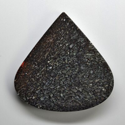 A black tear shaped stone on a white surface.