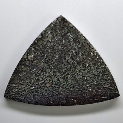 A triangular piece of stone on a white surface.