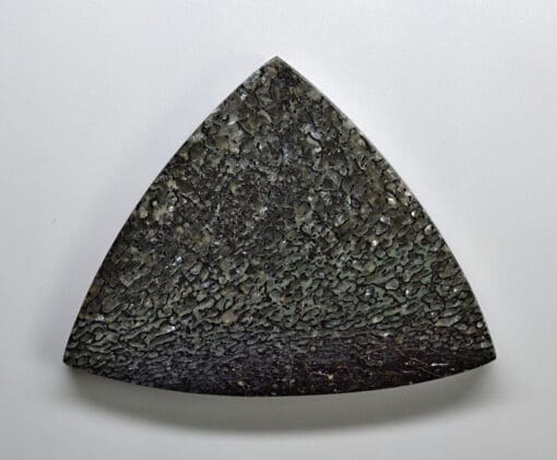 A triangular piece of stone on a white surface.