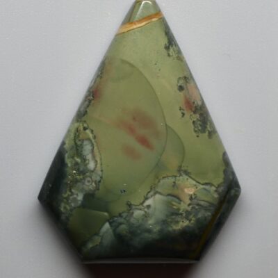 A green and red jasper pendant on a white surface.