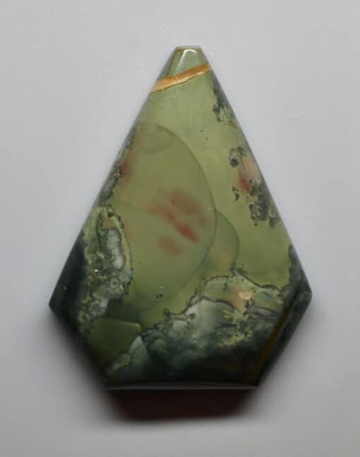 A green and red jasper pendant on a white surface.