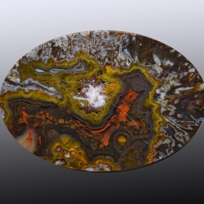A circular piece of agate with orange and yellow swirls.
