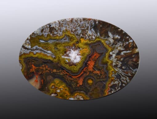 A circular piece of agate with orange and yellow swirls.