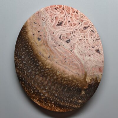 A round piece of wood with brown and pink swirls on it.