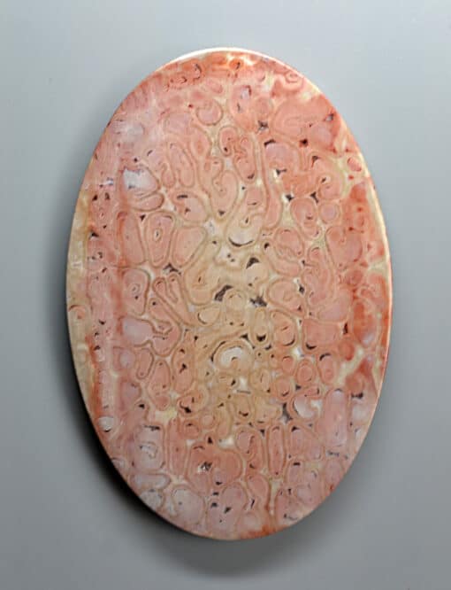 A pink marble plate with a design on it.