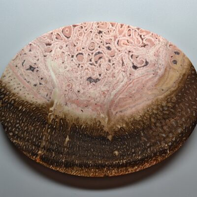 A wooden plate with pink and brown swirls on it.