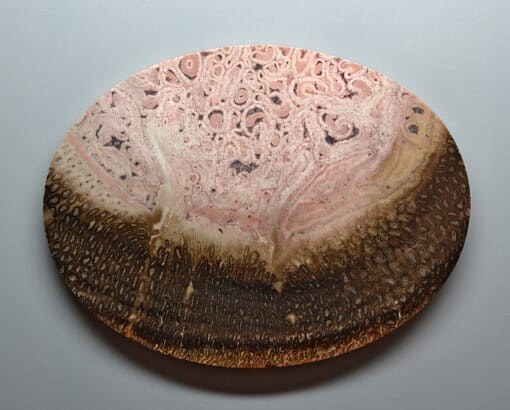 A wooden plate with pink and brown swirls on it.