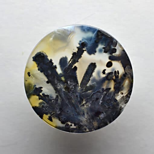 A round piece of agate with black and yellow paint on it.