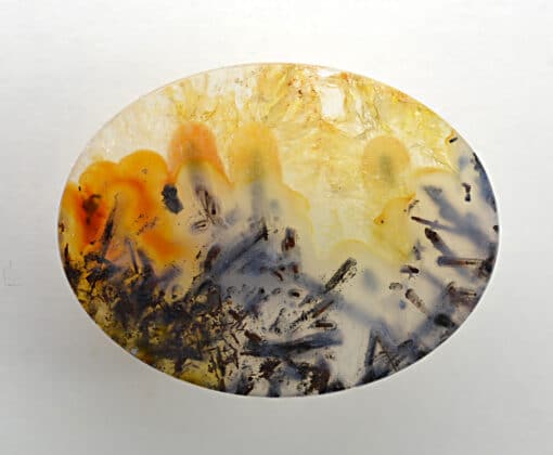 A round piece of agate with yellow and orange paint on it.