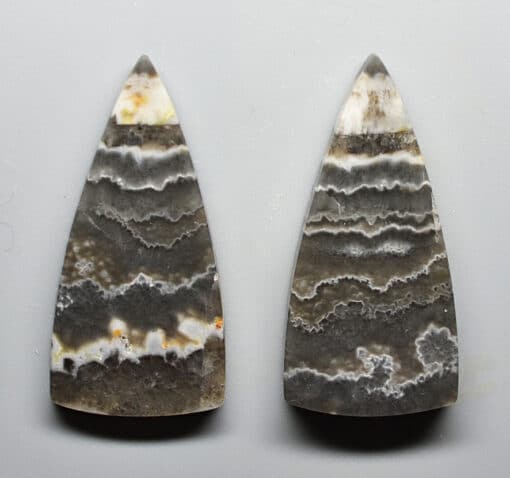A pair of agate arrowheads on a white surface.