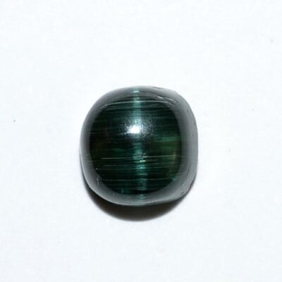 A green tiger eye stone on a white surface.