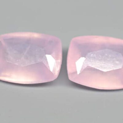 Two pink quartz cabochons on a grey surface.