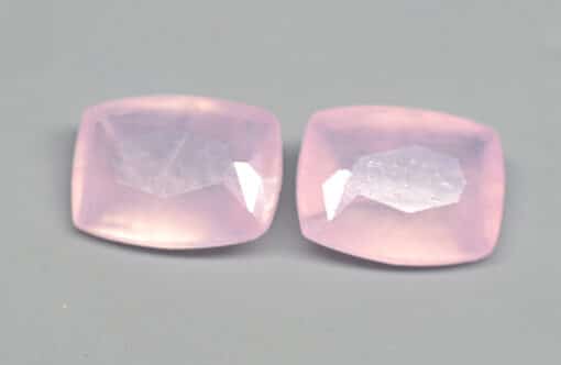 Two pink quartz cabochons on a grey surface.