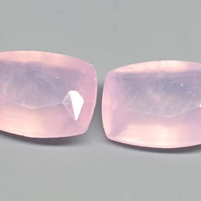 Two pink quartz cabochons on a grey surface.