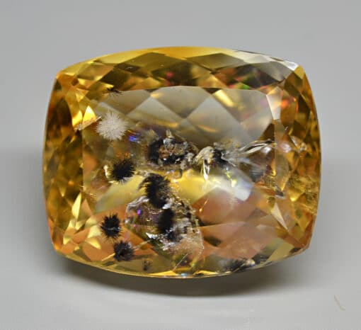 A cushion cut yellow sapphire with black specks.