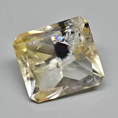A square cut yellow sapphire on a white surface.