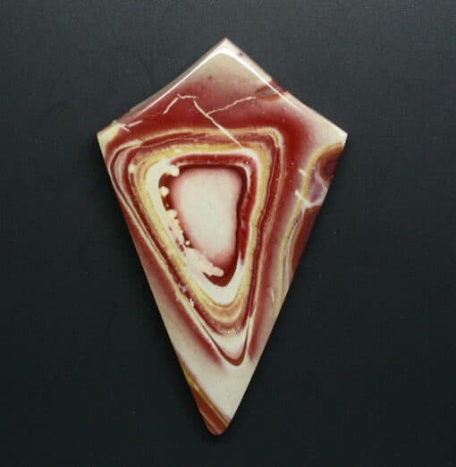 A piece of red and yellow agate on a black surface.