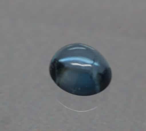 A blue sapphire on a grey surface.