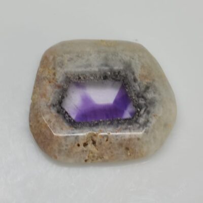 An amethyst stone on a white surface.