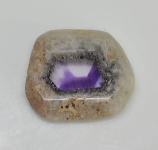 An amethyst stone on a white surface.