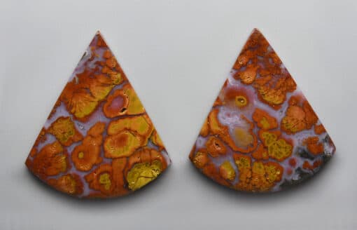 A pair of orange and yellow earrings on a white surface.