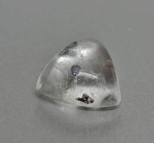 A small piece of clear quartz on a grey surface.