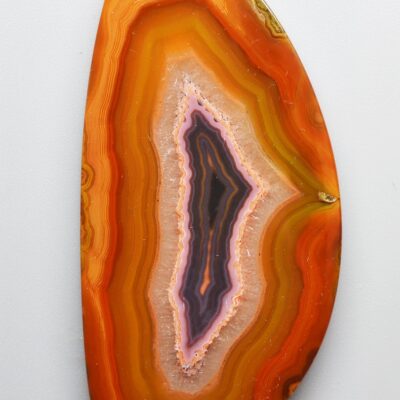 An orange and purple agate piece on a white surface.