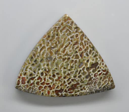 A triangular shaped piece of stone on a white surface.