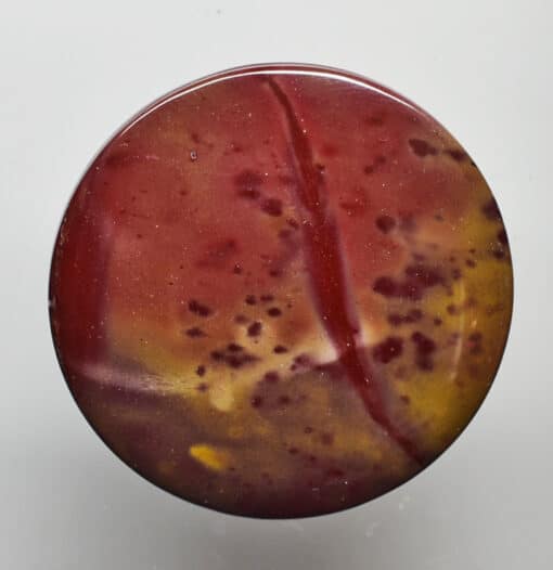 A red and yellow marble button on a white surface.
