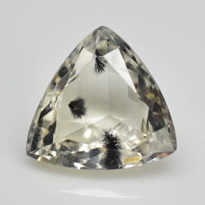 A triangular shaped yellow topaz on a white surface.