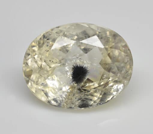 An oval cut white topaz stone on a white surface.