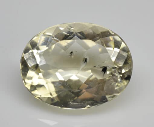 An oval cut white topaz stone on a white surface.