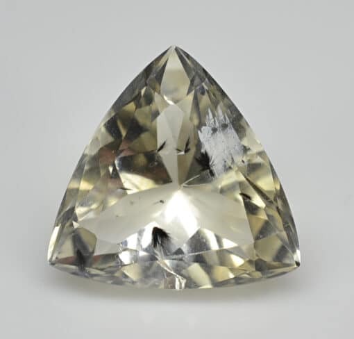 A triangular shaped yellow sapphire on a white background.